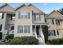 Charming townhome featuring gray siding, blue shutters, a quaint front porch, and a tidy, landscaped yard at 407 Whitehall Ct, Clayton, NC 27520