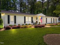 Charming white brick home with manicured lawn and mature trees offers classic curb appeal at 4112 Huckleberry Dr, Raleigh, NC 27612
