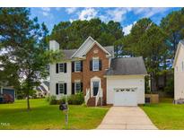 Charming two-story home with brick and white siding, attached garage, and a well-manicured front yard with mature trees at 805 Penncross Dr, Raleigh, NC 27610