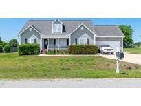 Charming home featuring manicured hedges, a gray exterior, and an attached garage at 104 Jj Dr, Benson, NC 27504