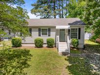 Charming single-story home featuring a well-maintained lawn and welcoming front entrance with stylish, light blue door at 1208 W Murray Ave, Durham, NC 27704