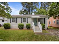 Charming single-story home with a tidy lawn, white siding, black shutters and a light-blue front door at 1208 W Murray Ave, Durham, NC 27704