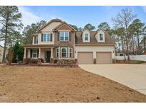 Charming two-story home featuring a covered porch, two-car garage, and beautifully manicured landscaping at 138 Tramway Cir, Angier, NC 27501