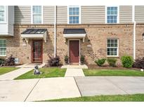 Charming townhome exterior featuring a brick facade, well-manicured lawn, and inviting front door at 1437 Newpoint Dr, Durham, NC 27713