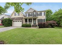 Charming two-story home featuring a landscaped front yard and a welcoming front porch with stone and siding accents at 1612 Rainesview Ln, Apex, NC 27502