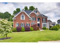 Beautiful brick home featuring a manicured lawn, mature trees, and colorful landscaping at 1637 Dodford Ct, Wake Forest, NC 27587