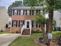 Charming two-story brick home with black shutters, a manicured lawn, and mature trees at 1937 Crag Burn Ln, Raleigh, NC 27604