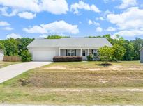 Charming single-story home with a well-manicured lawn and an attached two-car garage at 357 Sherrill Farm Dr, Benson, NC 27504