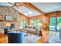 Bright living room featuring vaulted ceilings, wood paneling, a stone fireplace, and ample natural light at 37 Wedgewood Rd, Chapel Hill, NC 27514