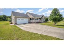 Charming single-story home featuring a two-car garage, welcoming front porch, and well-maintained landscaping at 59 Long Grass Dr, Smithfield, NC 27577