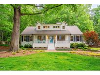 Charming traditional home featuring a bright blue door, white facade, landscaped yard, and welcoming front porch at 823 Churchill Dr, Chapel Hill, NC 27517