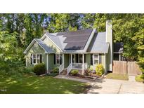Charming green home with gray roof, black shutters, solar panels, manicured lawn, and appealing curb appeal at 909 Alderleaf Dr, Fuquay Varina, NC 27526