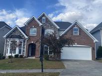 Two-story brick and stone home with attached two-car garage and manicured front yard at 104 Elmsford St, Durham, NC 27703
