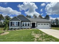 Charming single-story home with a manicured lawn and a two-car garage on a sunny day at 158 Sourgum Ct, Zebulon, NC 27597