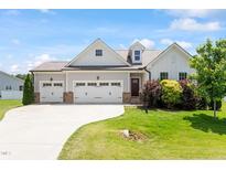 Charming home featuring a three-car garage and beautifully landscaped front yard at 164 Wilson Farm Ln, Clayton, NC 27527