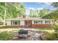Charming single-story home with a brick-and-painted facade, red brick chimney, and inviting walkway at 515 Poplar Dr, Raleigh, NC 27603