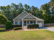 Charming single-story home boasts a well-manicured lawn, lush landscaping, and a welcoming front porch at 70 King Mackeral Ct, Willow Springs, NC 27592