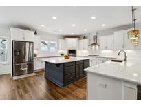 Modern kitchen with white cabinets, stainless steel appliances, an island, and hardwood flooring at 1211 Gloriosa St, Apex, NC 27523