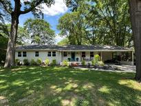 Charming single story home with an attached carport, landscaped yard, and a bright teal front door at 1409 E Martin St, Raleigh, NC 27610