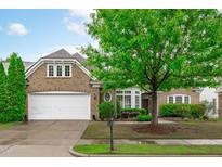 Charming brick home with manicured landscaping, mature tree, and a two-car garage at 208 Beckingham Loop, Cary, NC 27519