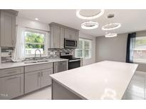 Modern kitchen features stainless steel appliances, grey cabinets, mosaic backsplash and island with white countertop at 2315 Oxford Rd, Henderson, NC 27536