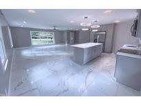 Bright open-concept kitchen features gray cabinets, a center island, stainless steel appliances, and gleaming marble floors at 2315 Oxford Rd, Henderson, NC 27536