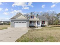 Charming single-Gathering home featuring a two-car garage and welcoming front porch with red shutters at 25 Mannford Ln, Angier, NC 27501