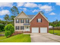 Charming two-story home featuring a brick and siding exterior, two-car garage, and well-manicured lawn at 32 Lattimore Rd, Cameron, NC 28326