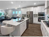 Bright kitchen boasts white cabinets, stainless steel appliances, and a large island with counter seating at 87 Addison Pond Ct, Zebulon, NC 27597
