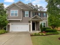 Charming two-story home with gray siding, black shutters, an attached two-car garage, and manicured landscaping at 8844 Forester Ln, Apex, NC 27539