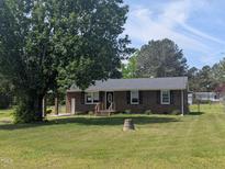 Charming single-story brick home with a well-maintained lawn and mature trees at 1064 Abbott Rd, Henderson, NC 27537