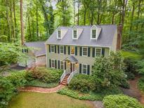 Aerial view of a two-story home surrounded by lush landscaping and mature trees, showcasing its elegant design at 12709 Timberlane Ct, Raleigh, NC 27613