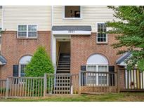 Charming townhome exterior with brick facade, complemented by yellow siding, and lush green landscaping at 2201 Mountain Mist Ct # 202, Raleigh, NC 27603