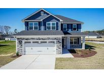 Charming two-story home boasts a striking blue exterior, complemented by a stone-accented garage and well-manicured landscaping at 301 New Twin Br Ct, Smithfield, NC 27577