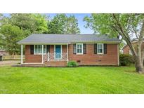Charming brick home featuring a well-manicured front yard, bright blue front door, and classic shutters at 307 Pine Tree Rd, Oxford, NC 27565