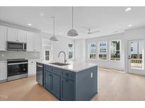 Bright kitchen featuring a large island with a sink, stainless steel appliances and wood floors at 5049 Lundy Dr # 101, Raleigh, NC 27606