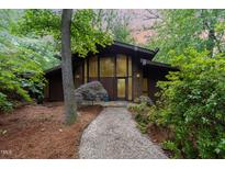Unique modern home with brick and wood exterior nestled in a lush wooded lot with mature landscaping at 612 Greenwood Rd, Chapel Hill, NC 27514