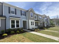 New townhomes with vinyl siding, stone accents, manicured lawns, and concrete sidewalks on a sunny day at 6443 Granite Quarry Dr, Raleigh, NC 27610