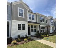 Charming townhome featuring a well-manicured lawn and a mix of siding, shingle, and stone architectural details at 6445 Granite Quarry Dr, Raleigh, NC 27610