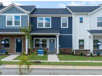Attractive townhome featuring blue and white exterior, a well-maintained lawn, and a sidewalk at 715 Chandler Stone Dr, Zebulon, NC 27597