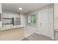 A well-lit kitchen features granite countertops, white cabinets, stainless steel appliances and a bright window at 101 Oyster Bay Ct # B2, Cary, NC 27513