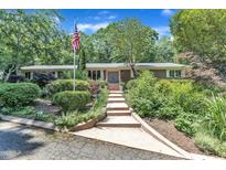 Charming one-story brick home with an American flag, lush landscaping, and inviting walkway at 10909 Raven Rock Dr, Raleigh, NC 27614