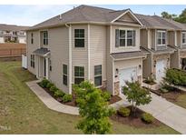 Two-story townhome features a one-car garage, neutral siding, manicured landscaping, and a concrete drive at 1136 Longitude Dr, Durham, NC 27713