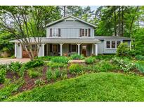 Charming two-story home with a landscaped front yard featuring lush greenery, flowerbeds, and a welcoming front porch at 1513 Dellwood Dr, Raleigh, NC 27607