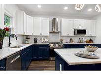 Modern kitchen featuring white cabinets, stainless steel appliances, and a stylish island with marble countertops at 2003 Pilot Mountain Ct, Apex, NC 27502