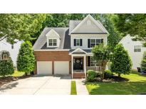 Charming two-story home featuring a brick facade, attached garage, and a well-manicured front lawn and a driveway at 303 Middleham Dr, Rolesville, NC 27571