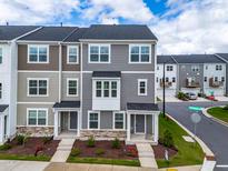 Modern townhome showcasing multiple gray tones, a covered entryway and manicured lawn with beautiful landscaping at 3101 Brellon Ln, Durham, NC 27703
