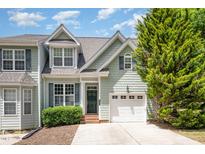 Charming townhome featuring a one-car garage, green siding, and a well-manicured lawn, inviting and full of curb appeal at 33 Grapevine Trl, Durham, NC 27707