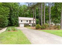 Split level home with beige siding, brick accents, metal roof, driveway, and mature landscaping at 5001 Simpson Dr, Sanford, NC 27330