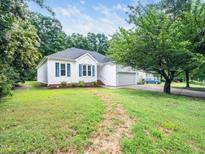 Charming single-story home with a well-manicured lawn and attached garage, nestled amongst mature trees at 102 Heritage Ridge Ct, Knightdale, NC 27545